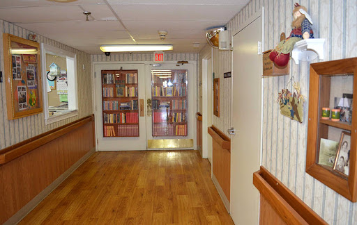 A peaceful hallway with wooden flooring and shelves filled with books.
