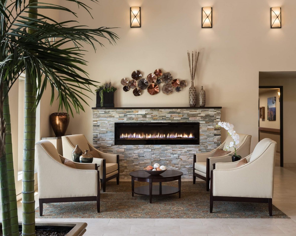 A modern living room featuring a sleek fireplace, elegant chairs, and tasteful decor.