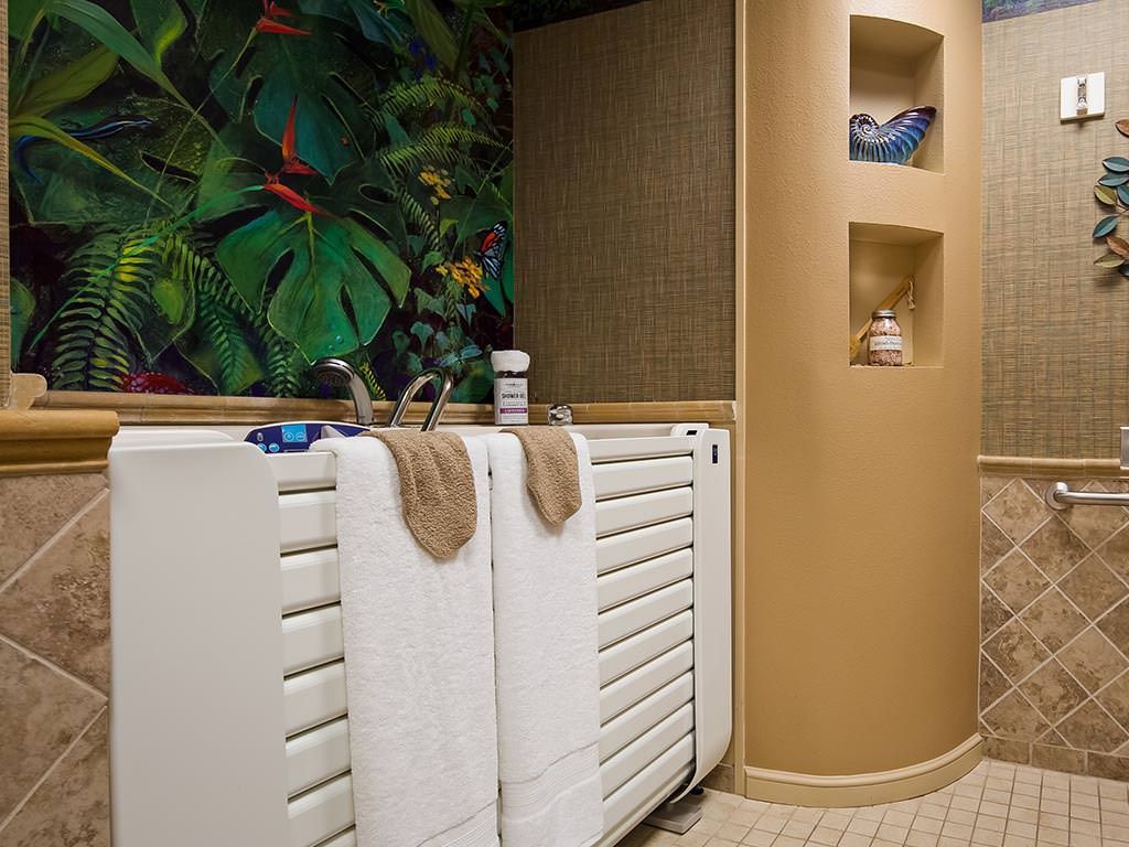 A stylish bathroom featuring a tropical-themed wall, white radiators with towels, and decorative niches.