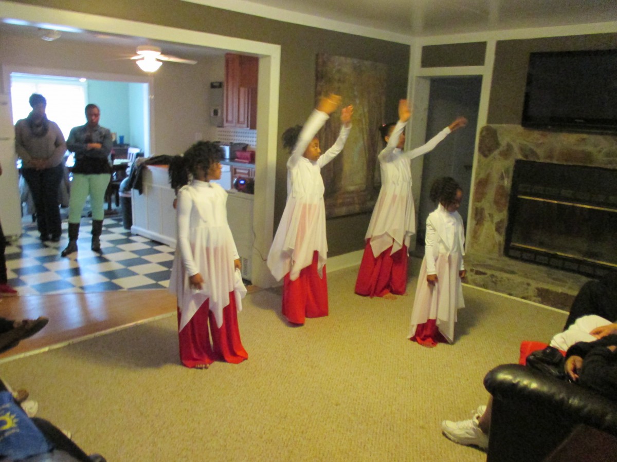 Children performing a dance routine indoors, dressed in white and red costumes.