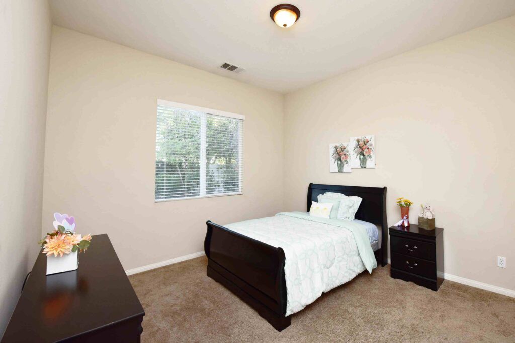 A simple, well-lit bedroom with a bed and basic furnishings.
