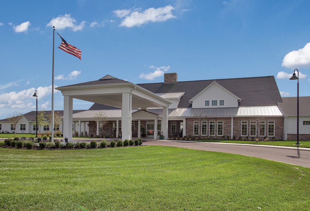 A large building with an American flag and a well-maintained lawn under a clear blue sky.