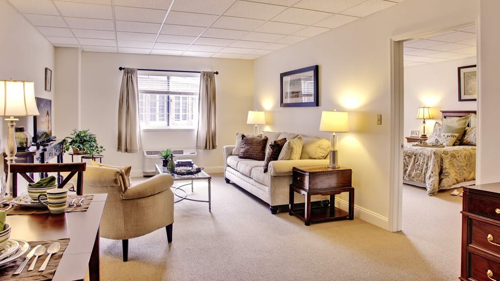 A well-lit living room with neutral colors, featuring a sofa, armchair, and coffee table.