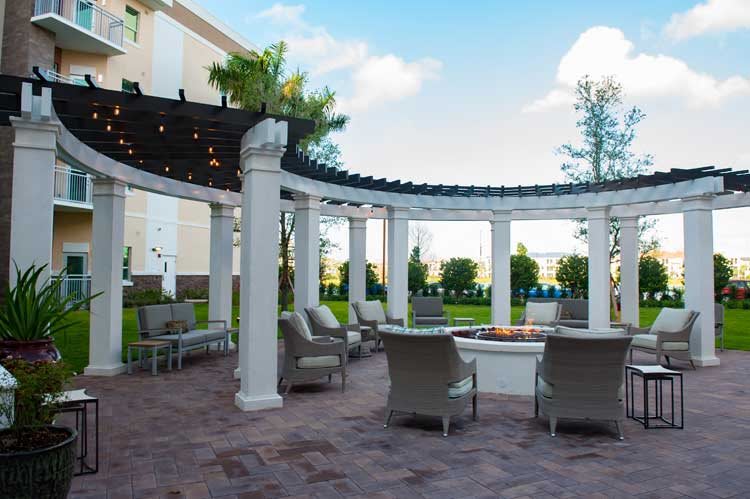 An outdoor patio with a pergola, featuring comfortable seating and a scenic garden view.