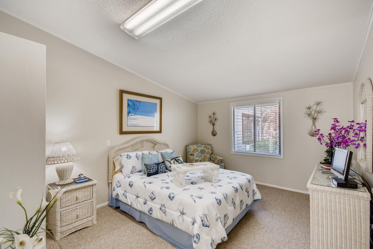A cozy bedroom with a bed, nightstands, and a window letting in natural light.