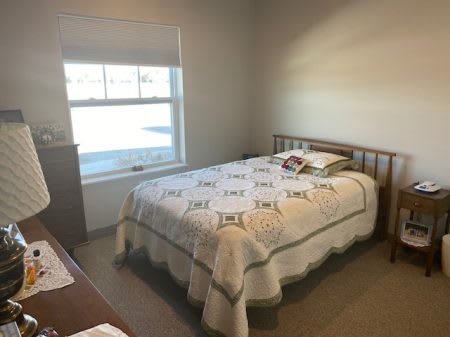 A cozy bedroom with a neatly made bed and a window letting in natural light.