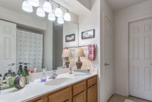 A clean and well-lit bathroom with a double sink vanity and decorative elements.