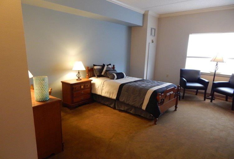 A cozy bedroom featuring a neatly made bed, wooden furniture, and soft lighting from a bedside lamp.