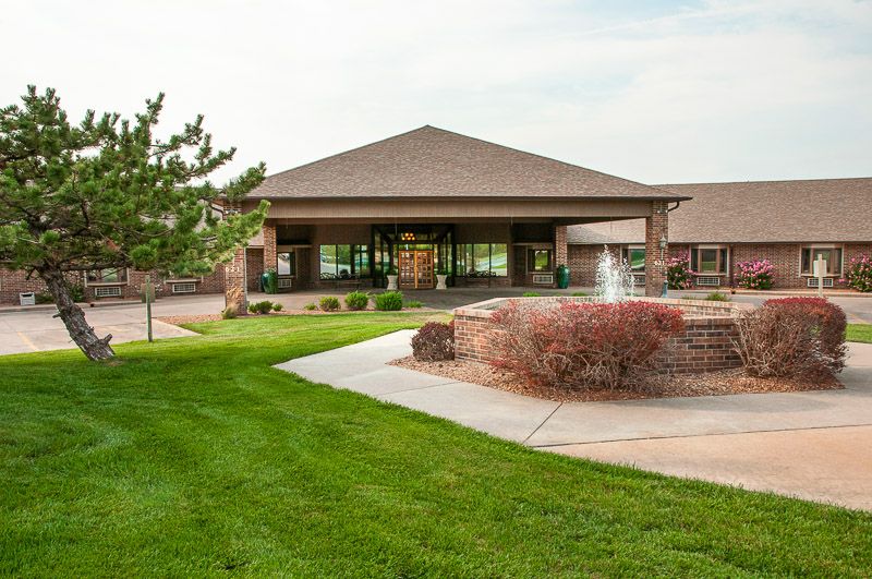 A modern building with a fountain surrounded by well-maintained greenery.