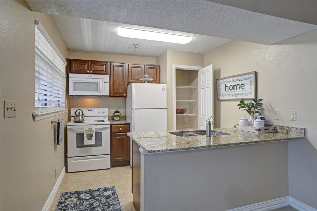 A cozy kitchen with cherry wood cabinets, a white refrigerator, stove, microwave, and a small island with a sink.