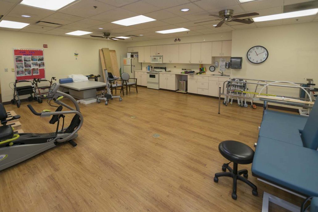 A spacious physical therapy and rehabilitation room with exercise equipment and therapy beds.