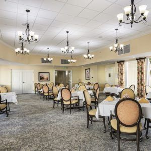An elegant dining room with neatly arranged tables and chairs under classic chandeliers.