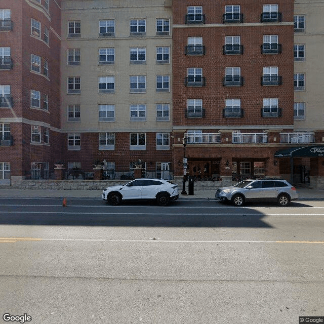 An urban street view with cars parked alongside a large apartment building.
