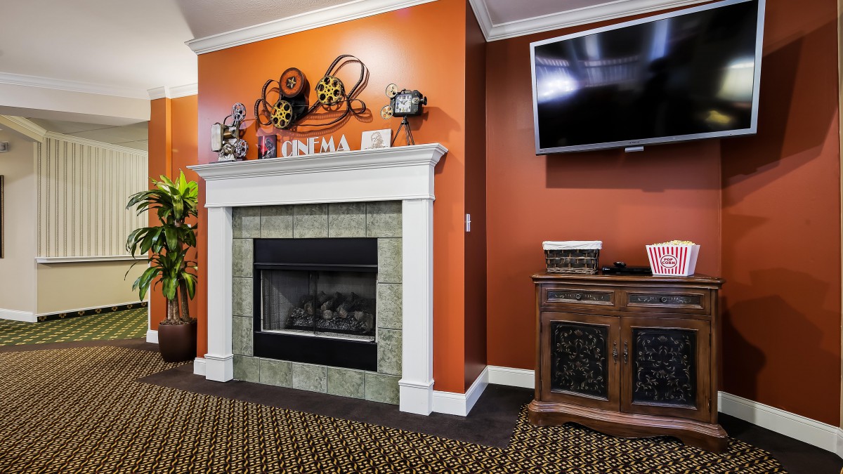 A cozy living room with an orange accent wall, featuring a fireplace and a mounted TV.