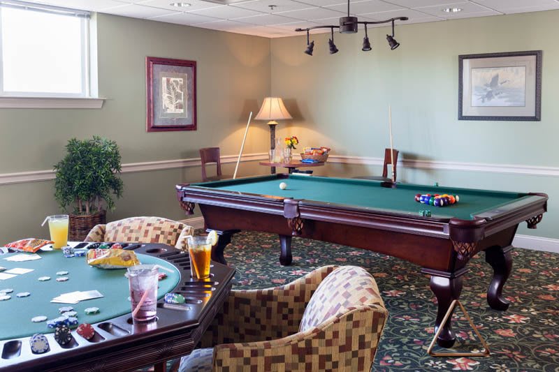 A cozy game room featuring a pool table and seating area with drinks.