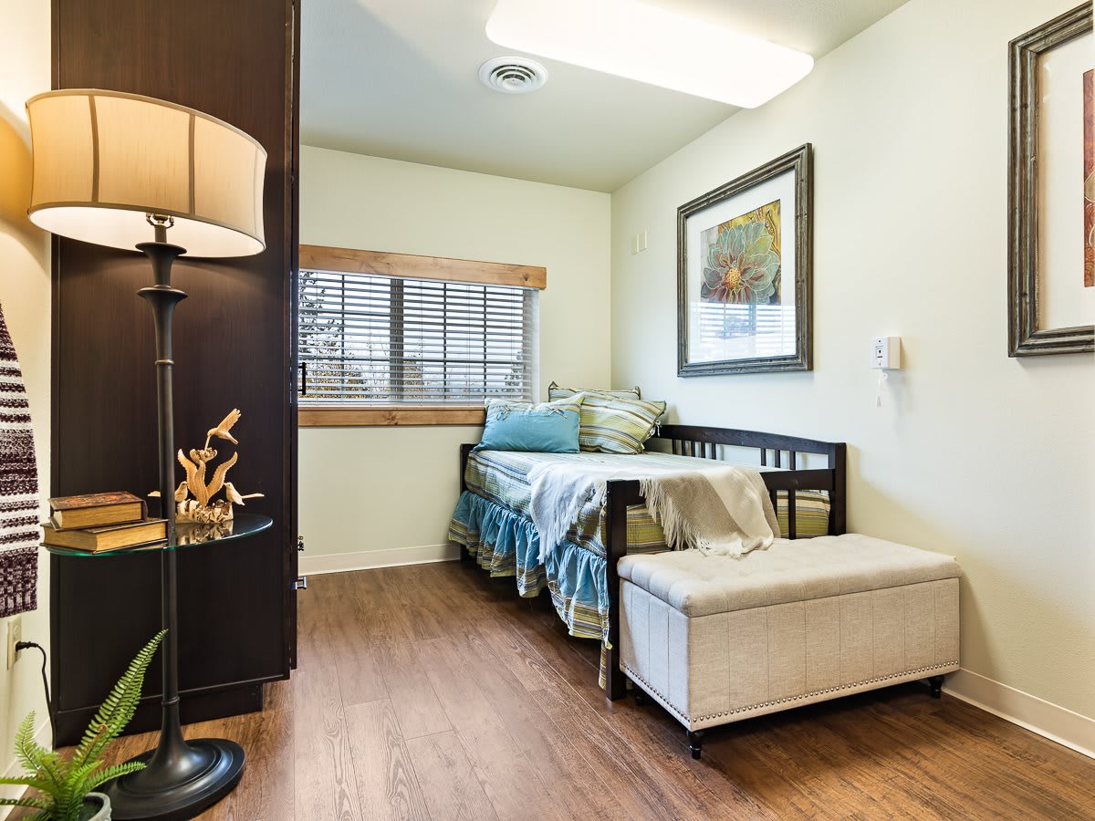 A cozy bedroom with a neatly made bed, decorative pillows, and a stylish ottoman.