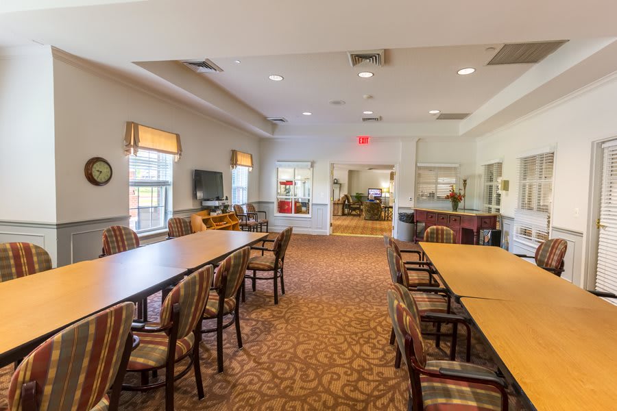 A spacious conference room with long tables and chairs, featuring large windows and bright lighting.