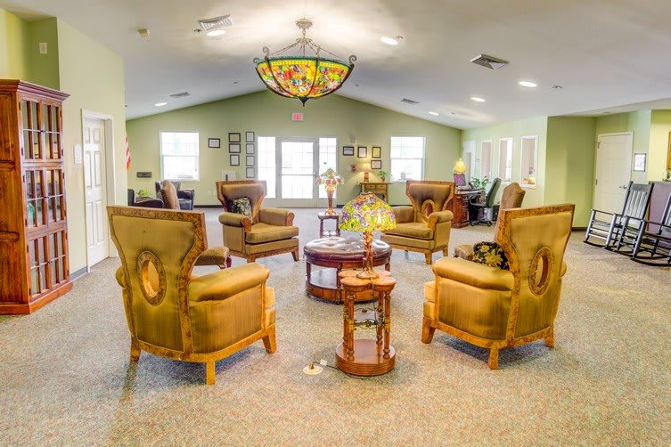 A warmly decorated living room with elegant chairs arranged around a central coffee table.