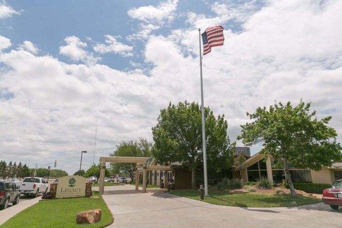 An entrance with an American flag flying on a cloudy day.