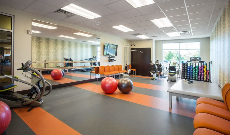 A modern gym with exercise equipment and medicine balls.