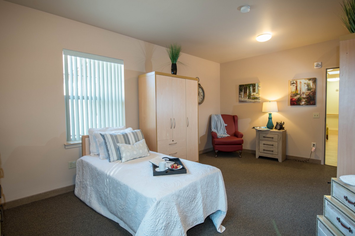 A cozy bedroom with a neatly made bed, wardrobe, and decorative elements.