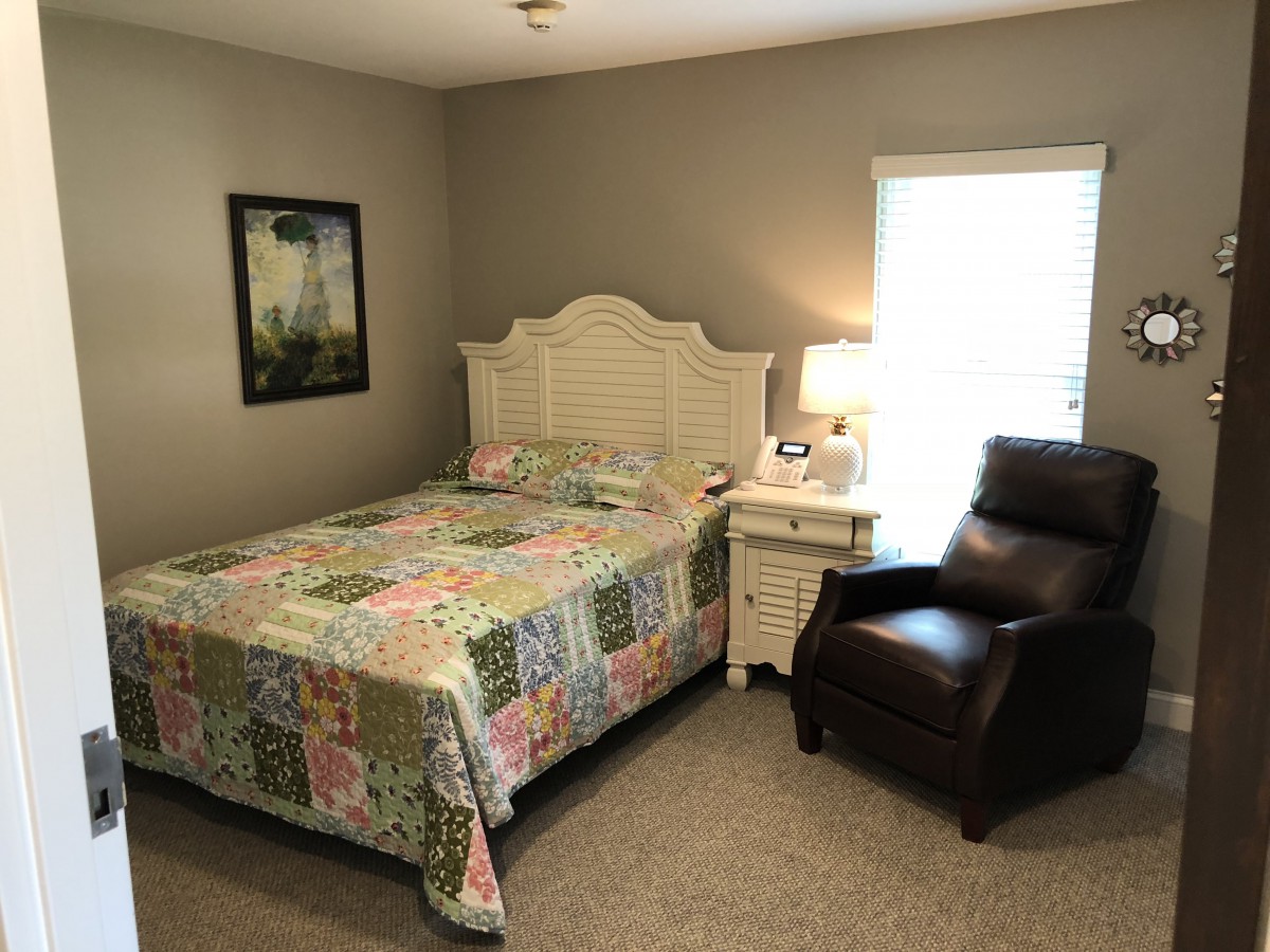 A cozy bedroom with a quilt-covered bed and leather armchair.