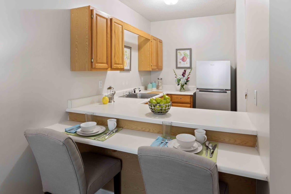A modern kitchen with a breakfast bar, featuring wooden cabinets and sleek appliances.