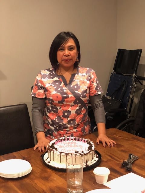 A woman standing in front of a birthday cake on a table.