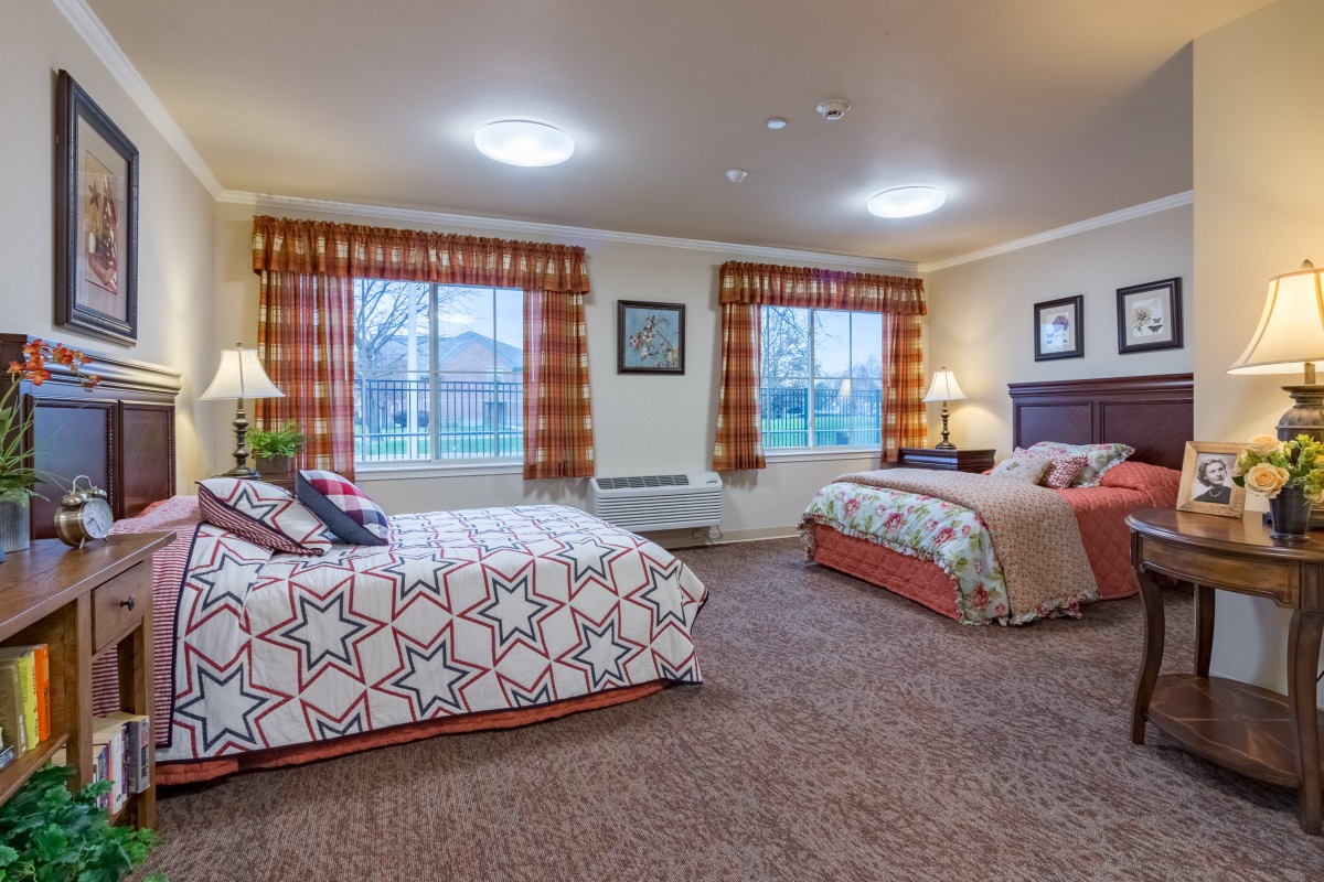 A cozy hotel room with two double beds, warm lighting, and patterned curtains.