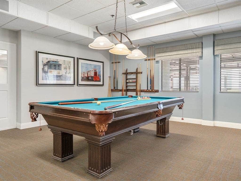 A well-lit game room featuring a classic pool table and decorative wall art.