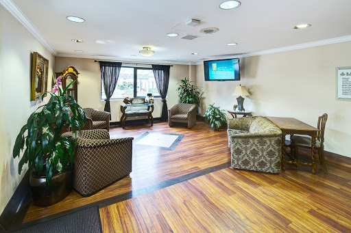 A cozy lobby area featuring comfortable seating, greenery, and a television.