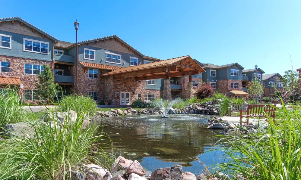 A picturesque building with a pond and fountain in the foreground, surrounded by lush greenery.
