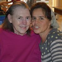 Two women smiling together indoors.