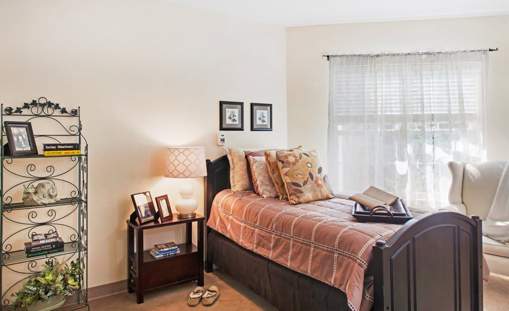 A cozy bedroom with a neatly made bed, decorative pillows, and a bedside table with a lamp.