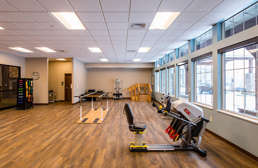 A well-lit and spacious gym area equipped with various exercise machines and open workout spaces.