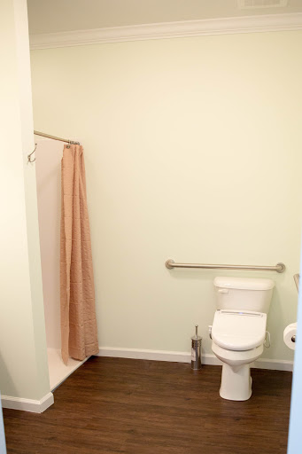 A minimalist bathroom featuring a toilet and a shower area with light green walls.