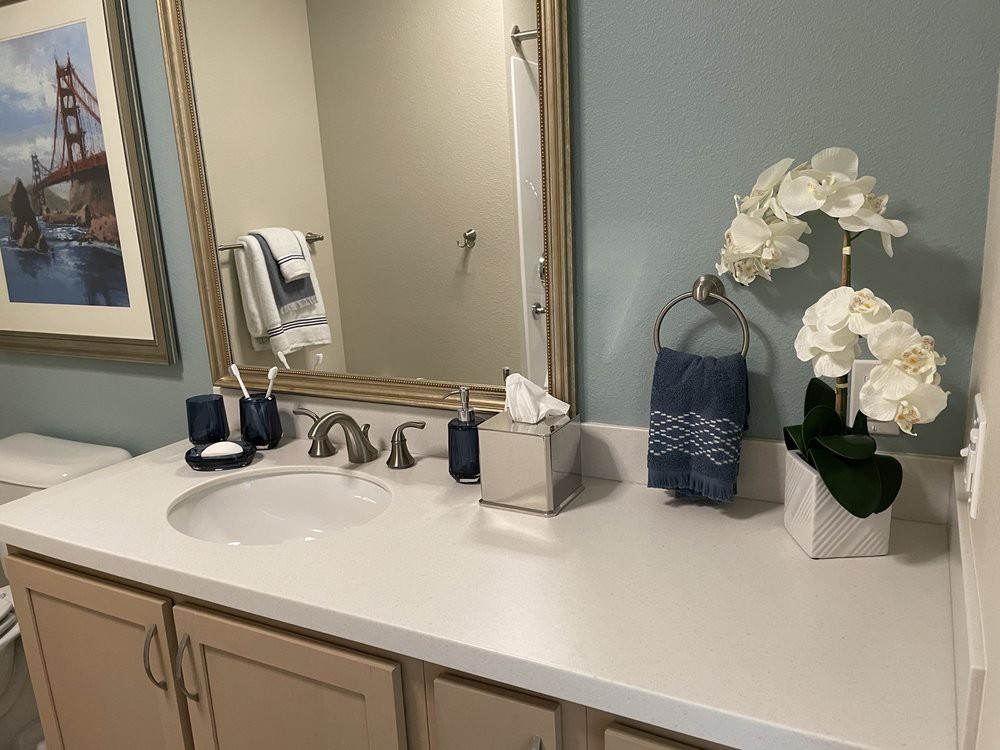 A well-organized bathroom countertop with a mirror, decorative flowers, and toiletries.