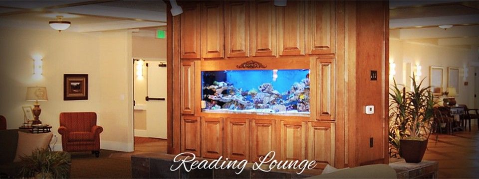 A cozy reading lounge featuring a built-in aquarium with vibrant marine life.