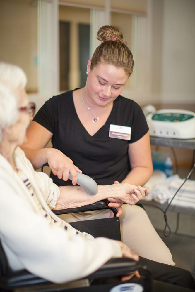 A caregiver providing therapy to an elderly woman.