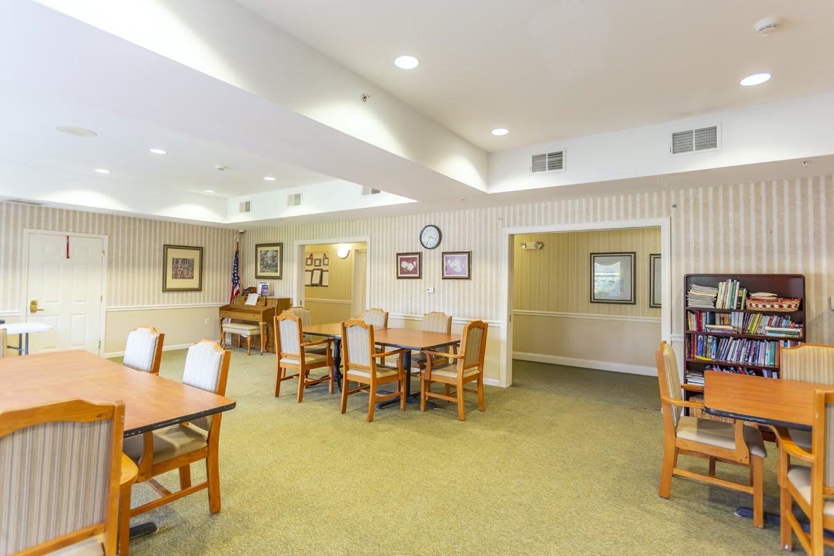 A spacious dining area with multiple tables and chairs, featuring warm lighting and decorative elements.