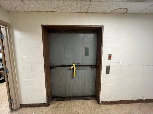 A closed elevator door secured with yellow safety tape, indicating it's out of service.