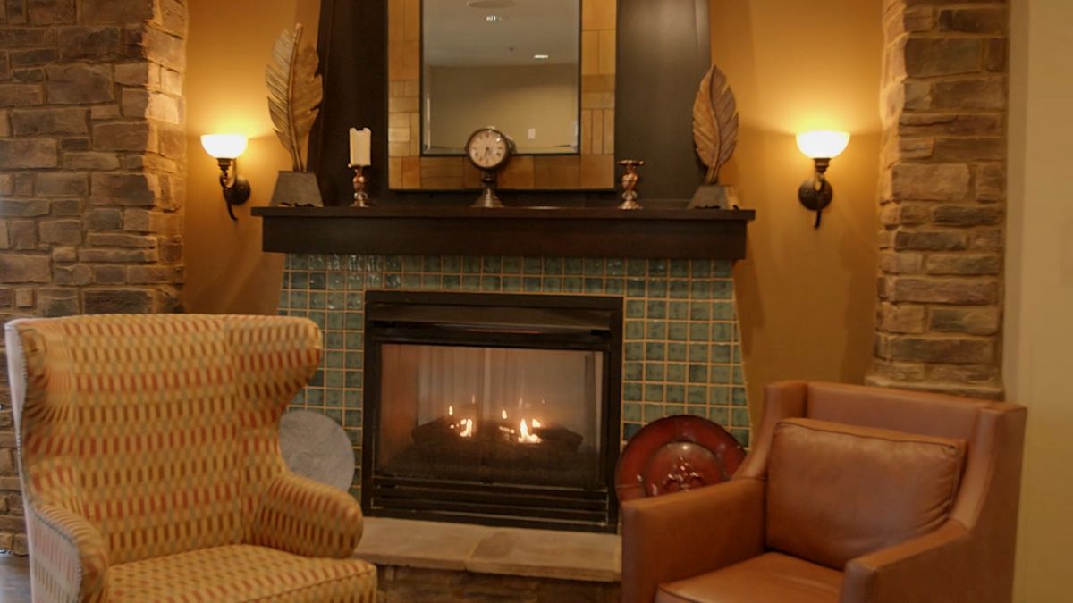 A cozy living room with a warm lit fireplace and comfortable seating.