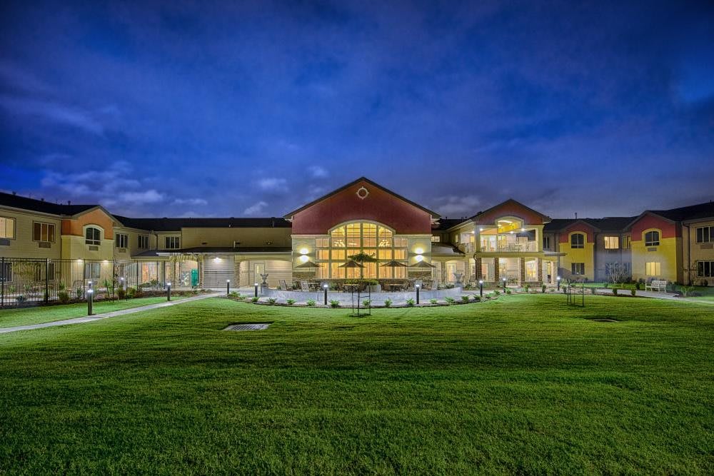 A well-lit building with surrounding lawns at night.