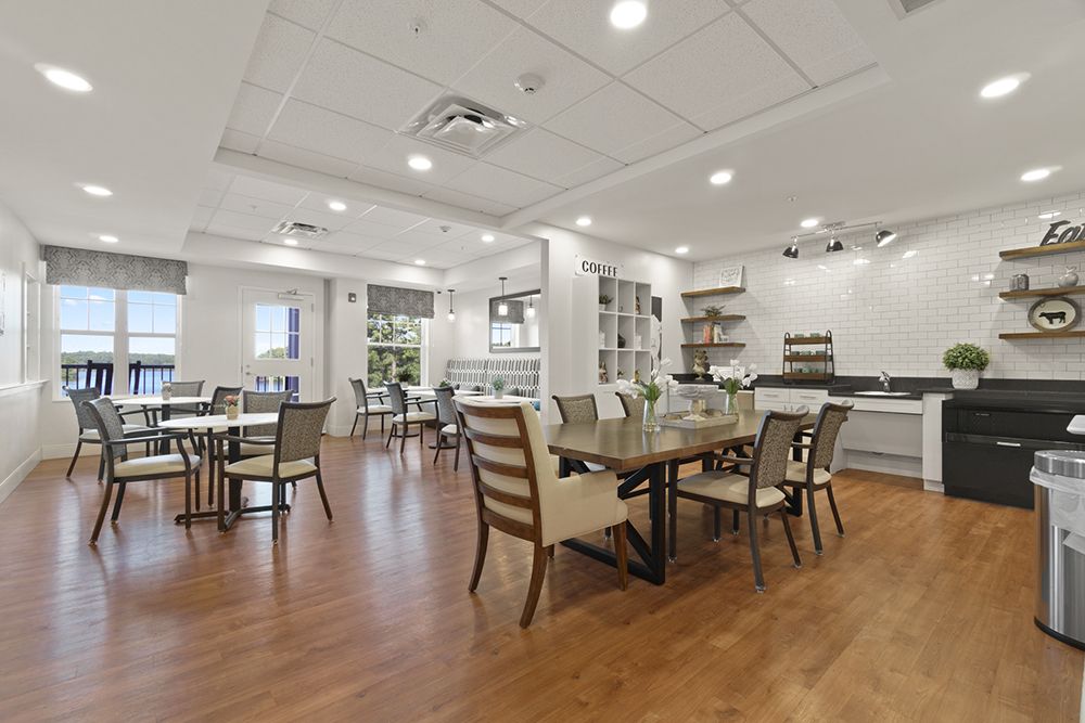 A modern dining area with tables and chairs, featuring bright lighting and a wooden floor.