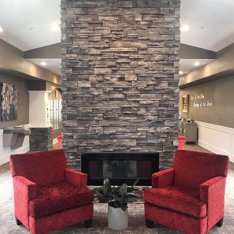 A cozy living room featuring a stone fireplace flanked by two red armchairs.