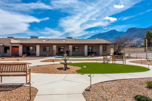 A serene outdoor area featuring a building, pathways, and landscaped gardens under a clear blue sky.