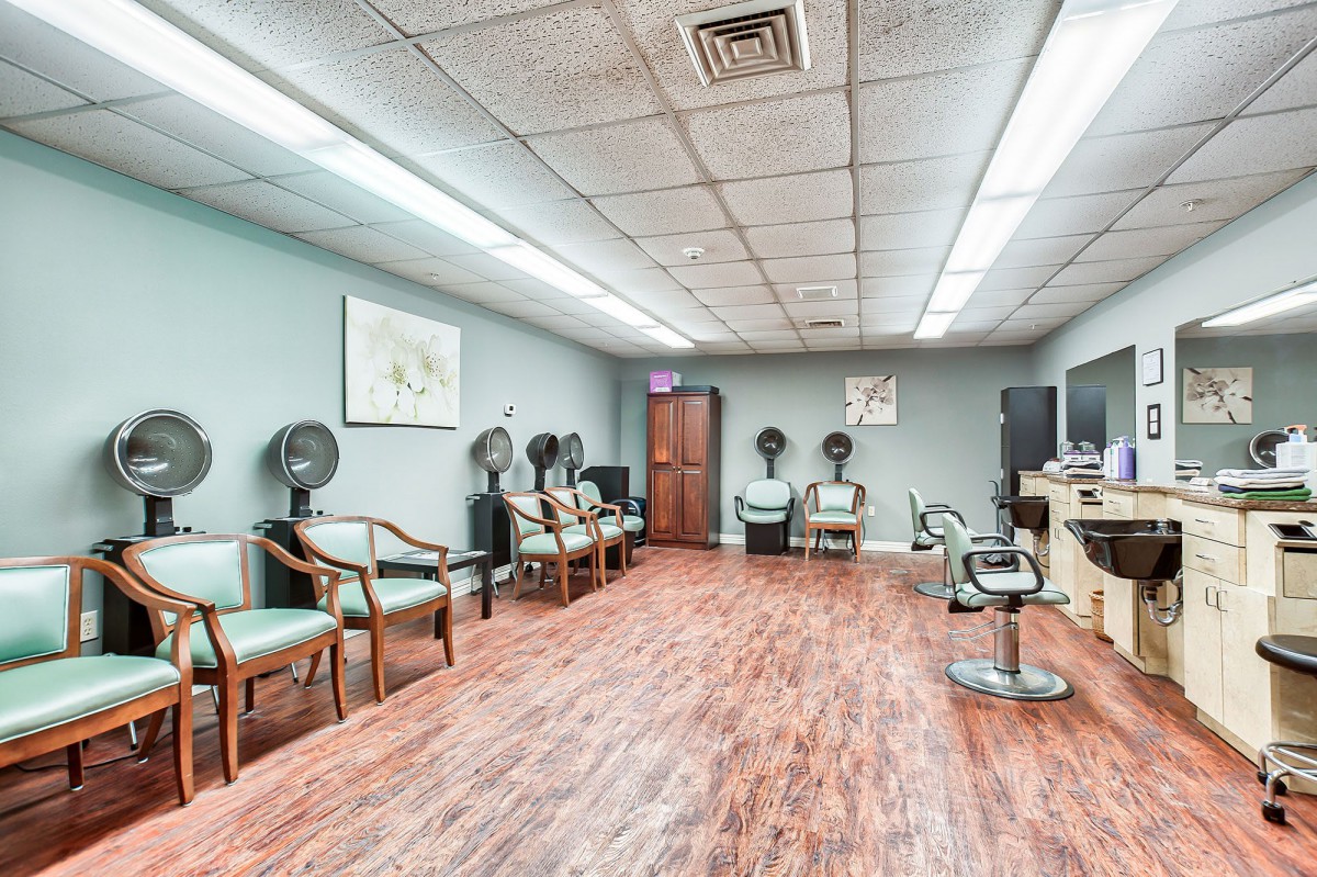 Interior of a salon featuring chairs and hairdryers.