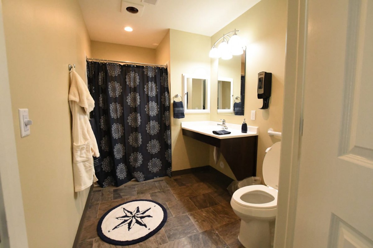 A well-lit bathroom with a shower curtain, sink, mirror, and toilet.
