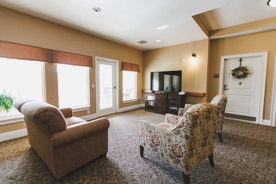 A cozy living room with a sofa, patterned chairs, and a television.