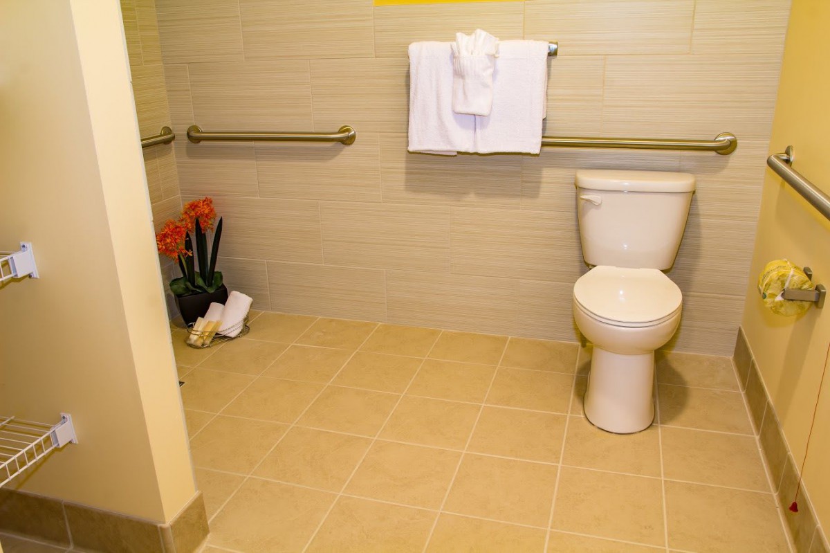 An accessible bathroom with a toilet, grab bars, and folded towels.